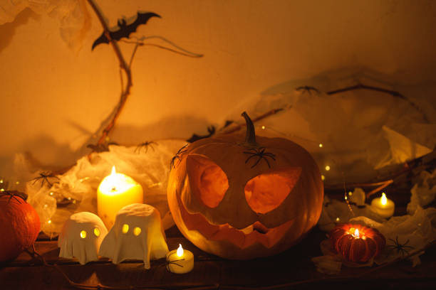 istock Happy Halloween! Spooky Jack o lantern pumpkin, glowing ghosts, spiders and bats in dark. Atmospheric halloween decor on table. Trick or treat 2171643377