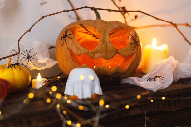 istock Happy Halloween! Scary pumpkin, glowing ghosts, spiders and bats on table. Halloween decor with spooky Jack o lantern and candles, space for text. Trick or treat 2171643417