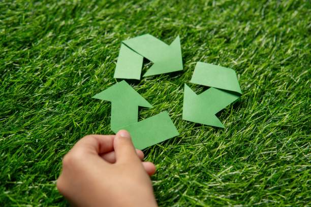 istock A child's hand holding a green paper arrow forming a triangular loop on a grassy background. 2171645619