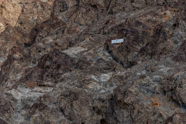 Sea level marker on the rocky cliffs above Badwater Basin in Death Valley, California, highlighting the stark difference between the landscape and sea level in the lowest point in North America.