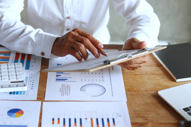 istock Businessman hand using pen, notebook and desktop summarizing company profit with success graph, checking quarterly report results. 2171648885