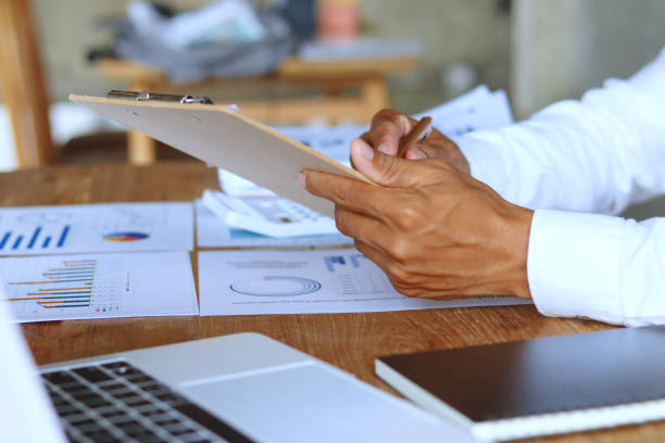 istock Businessman hand using pen, notebook and desktop summarizing company profit with success graph, checking quarterly report results. 2171648962