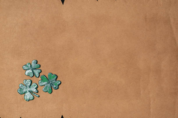 Close-up image of three green shamrock leaves on a brown paper background with jagged edges, perfect for St. Patrick's Day themes, luck, and natural decorations.St. Patrick's Day abstract background with copy space