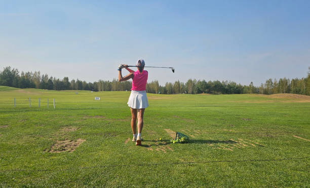 istock A golfer practices their swing on an open driving range surrounded by green fields and trees in bright daylight 2171654770