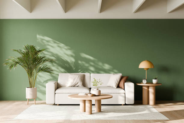 istock Modern living room with a green accent wall, a white sofa, a small table with a lamp, a coffee table, and a potted plant casting shadows on the wall. 3d render. 2171657364