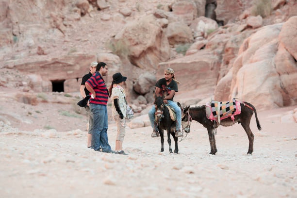 Petra, Jordan - April 16, 2023: Travelers engage with local guides in Petra, Jordan, as they ride donkeys to explore the ancient sites surrounded by stunning rock formations.