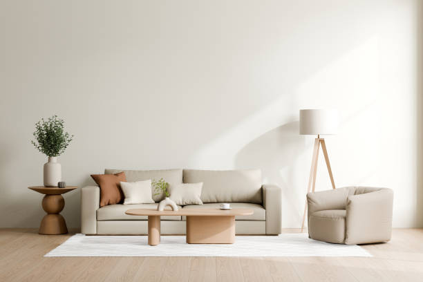 istock Elegant minimalist living room featuring a comfortable beige sofa, a round coffee table with decor, a pouf chair, a lamp, and a potted plant, 3d render. 2171660644