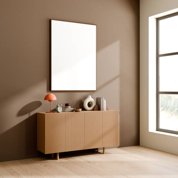 istock Sleek wooden sideboard adorned with various decor items, set against a brown wall with a blank picture frame above, 3d render. 2171660672