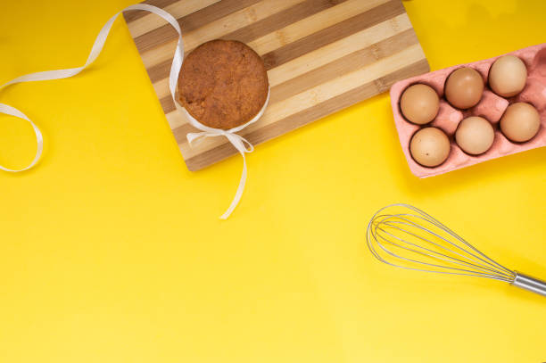 istock Easter pastries on the table with chicken eggs and a whisk on a yellow background. Top view 2171660897