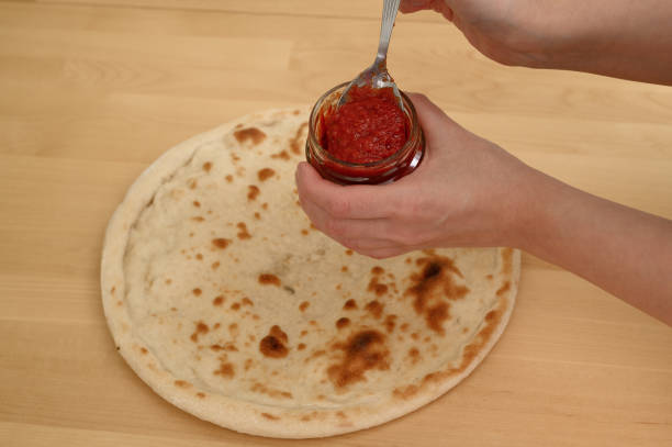 Putting tomato sauce on a pizza base, Italian cuisine,