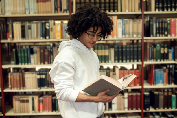 istock Curly-haired young man in eyeglasses in the library 2171664014