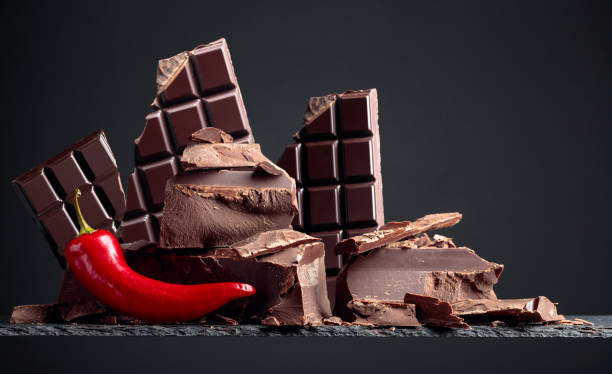 Black bitter chocolate with hot red pepper on a black background. Copy space.