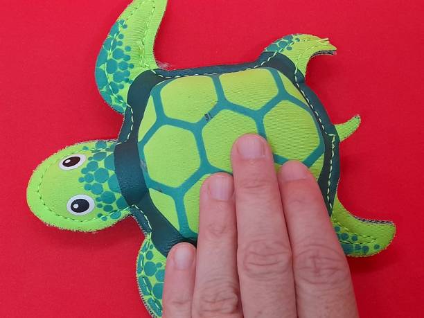 istock Green turtle figure with hand and red background 2171667201