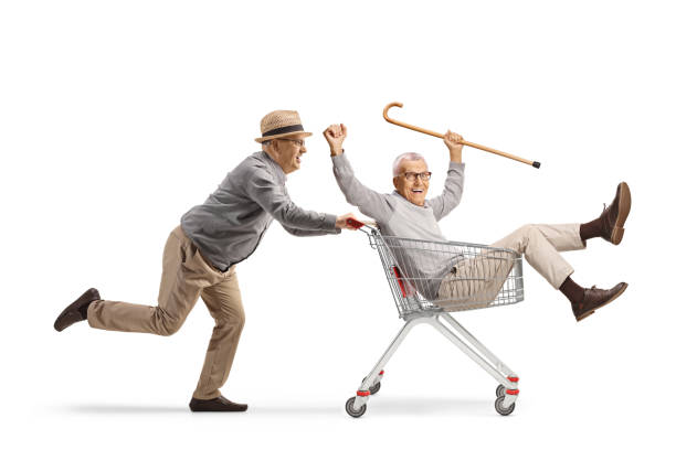 istock Elderly man having fun and pushign a friend inside a shopping cart 2171667927