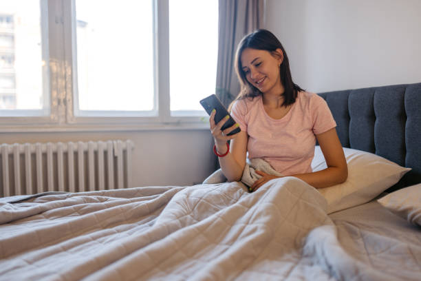 istock Young Woman Using Phone After Waking Up In The Morning 2171669811