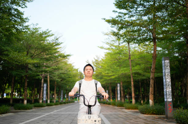Young Asian man with bicycle at public park