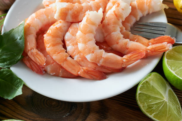 istock Fresh raw shrimps on plate with lime on wooden table, closeup 2171671021