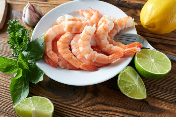 istock Shrimps on a plate with lime and herbs on wooden background 2171671027