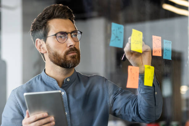 Focused businessman brainstorming with sticky notes during meeting in office