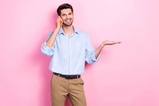 Photo of cheerful nice man speaking iphone presenting empty space recommend device shop novelty speed 4g isolated on pink color background
