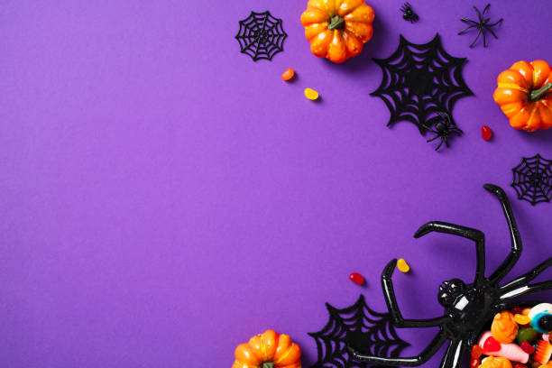 istock Halloween composition. Frame of Halloween decorations, pumpkins, spider with candies on violet background. Flat lay, top view, copy space 2171674152