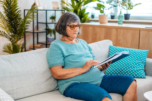 istock Senior Woman Sitting On The Sofa And Reading A Book 2171676448