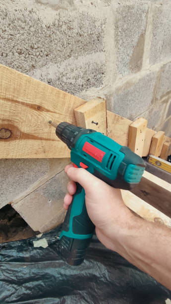 istock Electric drill on a construction site. The screwdriver in the master's hand closeup. Building concept. Stairs. The staircase structure. 2171676953