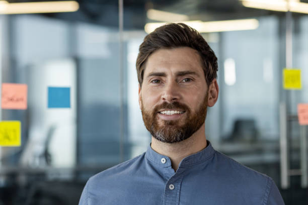istock Confident businessman with beard smiling in office setting with glass walls and sticky notes 2171677106