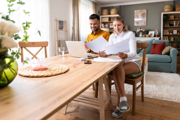 istock Working at home. Young freelance couple work from home office on laptop computer having video call with clients, showing statistics of business improvement with sales graphic printed on paper. 2171682252