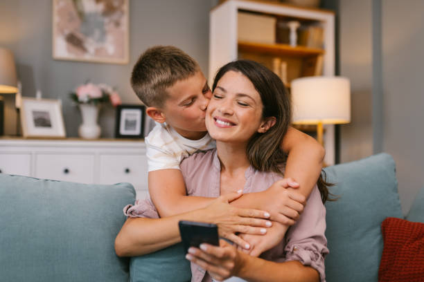 istock Son Kisses Mother While Hugging Her on the Sofa 2171682597