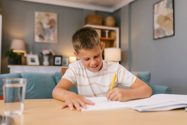 istock Young Boy Smiling While Doing Homework in a Cozy Living Room 2171682673