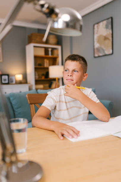 istock Young Boy Thinking While Doing Homework in a Cozy Living Room 2171682728