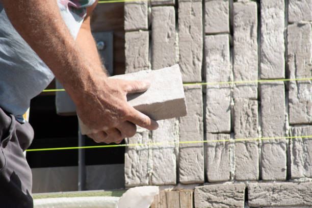 Builder aligning bricks on wall with level, tools in background, Concept of precision in construction work,