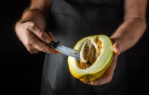 istock A chef peels a melon with a knife before serving it. Concept on a black background of preparing a healthy dessert 2171692512