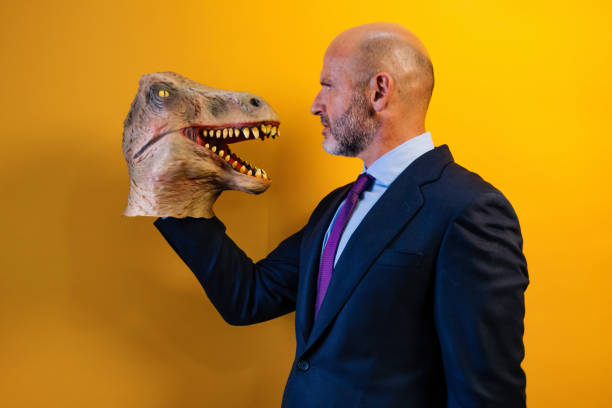 istock A man wearing a dinosaur mask in his hand on a yellow background. 2171692524