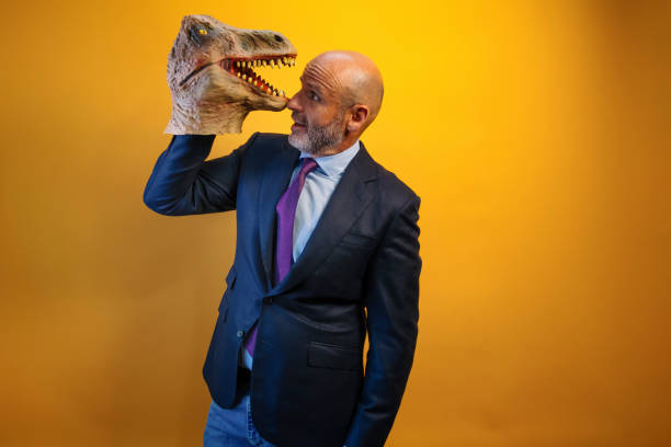 istock A man wearing a dinosaur mask in his hand on a yellow background. 2171692534