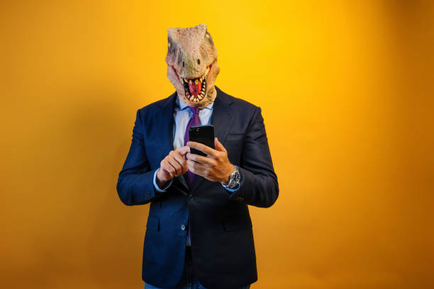 istock A man wearing a dinosaur mask using a smart phone on yellow background. 2171692586