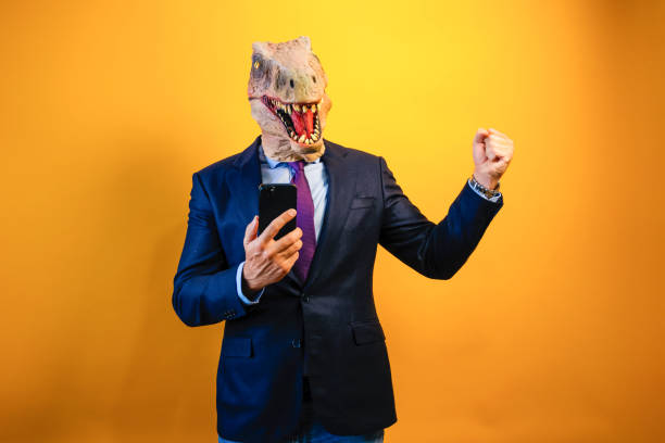istock A man wearing a dinosaur mask using a smart phone on yellow background. 2171692587