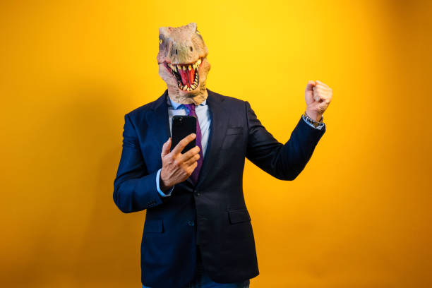 istock A man wearing a dinosaur mask using a smart phone on yellow background. 2171692608