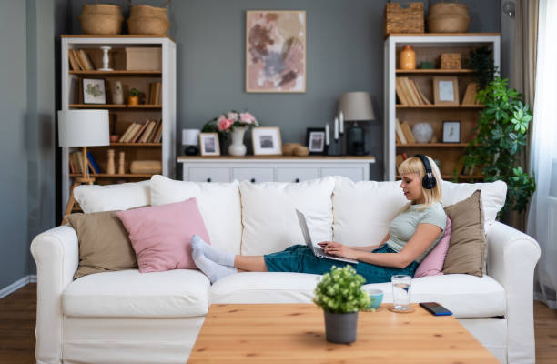 istock Young happy freelance worker or university student woman sitting work at home on sofa working on laptop, while listening podcast or listen the music, favorite song, enjoying freedom and independence. 2171694565
