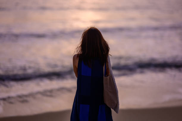 Portrait of a beautiful Asian woman relaxing on the beach at sunset. Charming and calm woman breathing fresh air at summer beach with copy space.