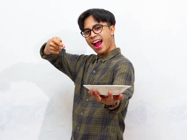 istock Handsome young Asian man pointing at an empty plate with an excited and happy expression, isolated on a white background. 2171700451
