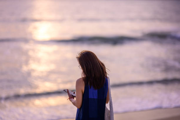 Portrait of a beautiful Asian woman relaxing on the beach at sunset. Charming and calm woman breathing fresh air at summer beach with copy space.