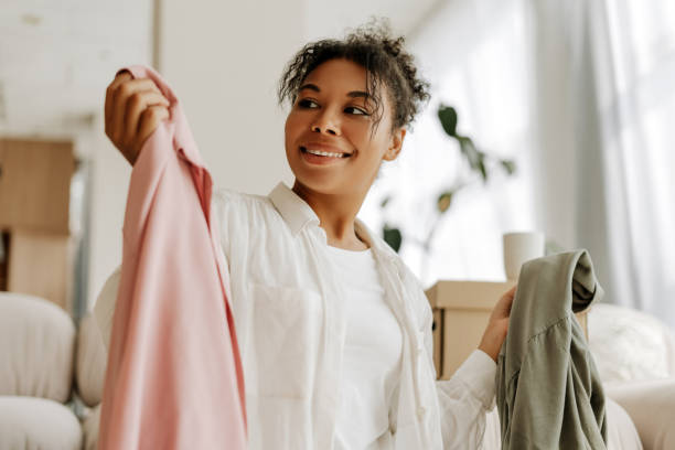 istock Young woman choosing clothes while unpacking after moving house 2171700814