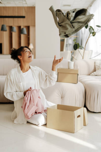 istock Woman having fun while packing clothes for donation in living room 2171700979