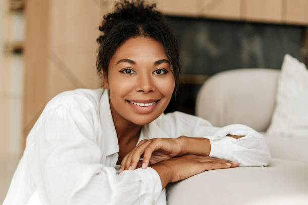istock Beautiful black woman smiling while relaxing on sofa at home 2171701215