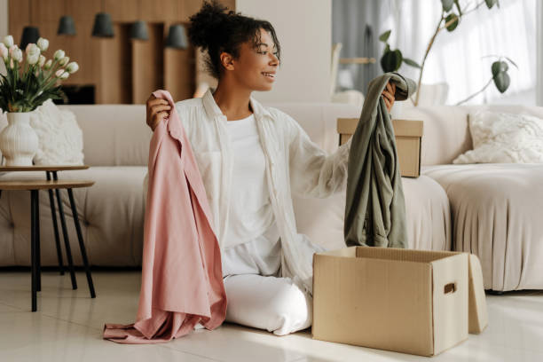 istock Young woman choosing clothes while unpacking boxes at home 2171701219