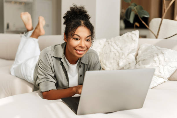istock Young woman relaxing on couch using laptop at home 2171701346