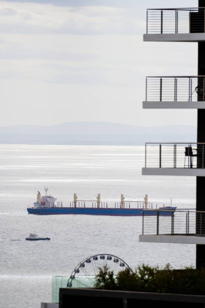 Empty Cargo Ship entering Cape Town with Robben Island backdrop, Cape Town, South Africa.  A big ferris wheel can be seen in the picture.
