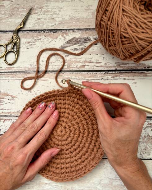 istock Female's hands with painted nails crocheting on a wooden surface 2171701627